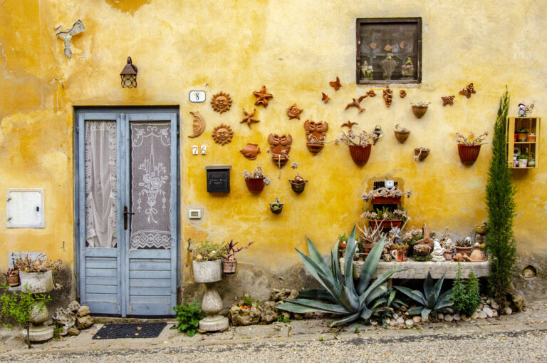 Exterior of Tuscan home with decorative wall art and potted plants
