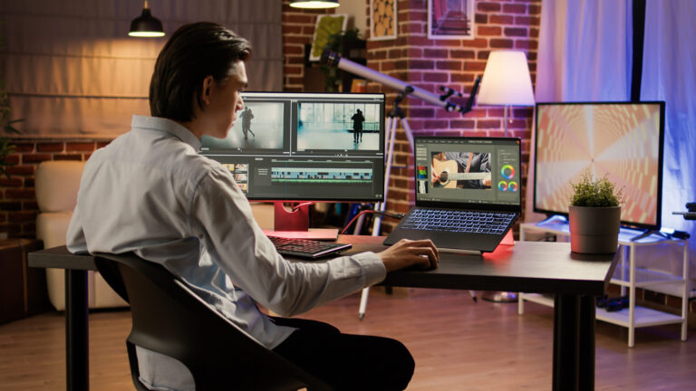 Videographer editing footage with visual effects on computer and laptop
