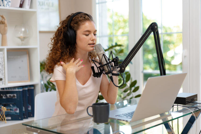 Young woman recording podcast at home with microphone and laptop.