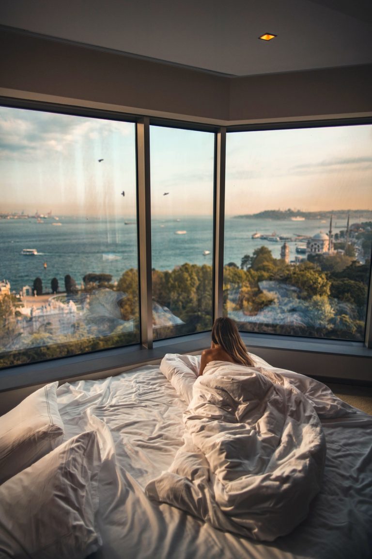 a person sitting on a bed looking out a window