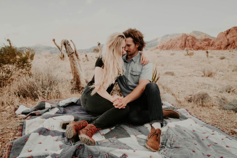 a man and woman sitting on a rock in the desert